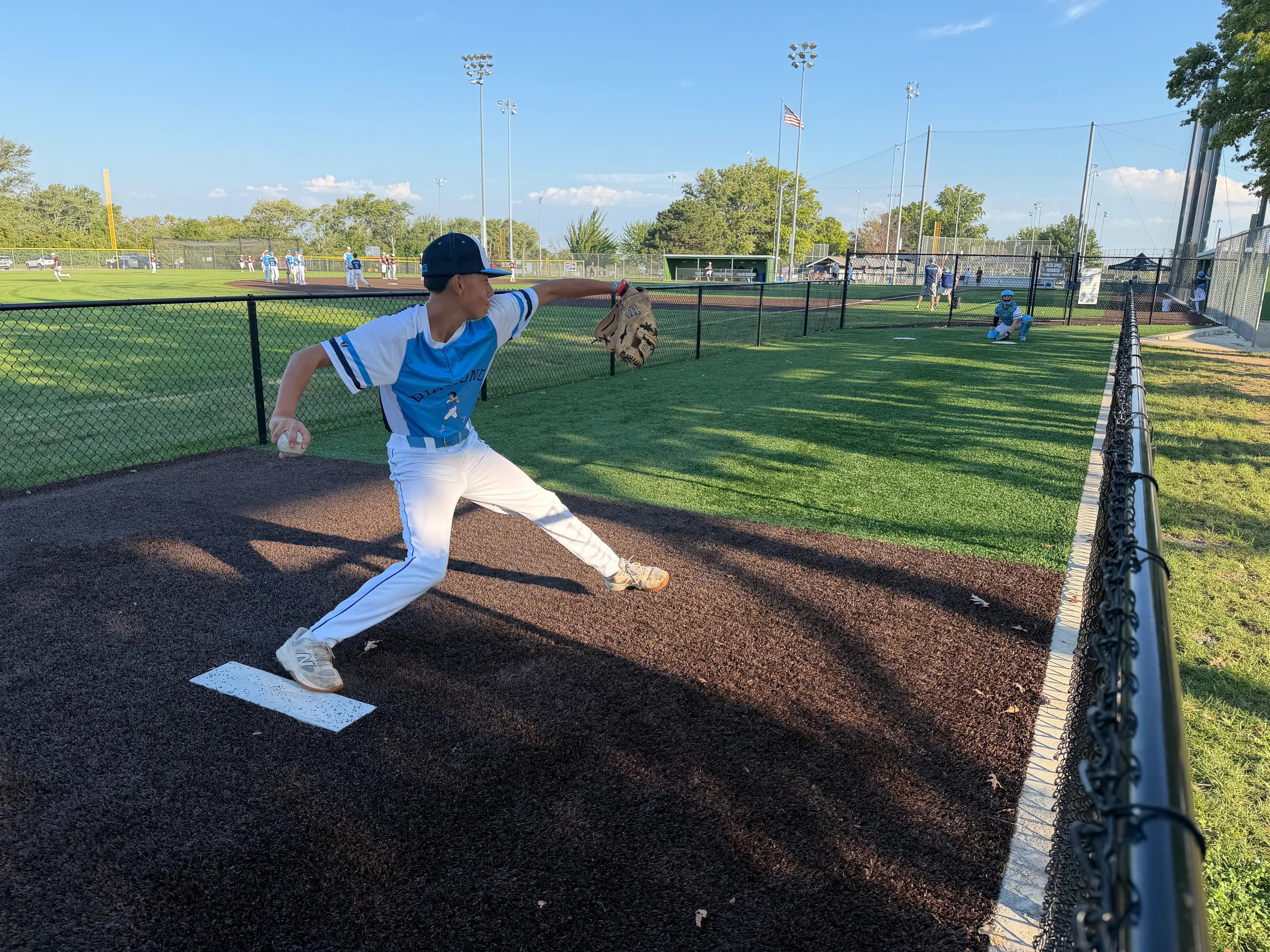 A pitcher warming up in the bullpen at a baseball complex