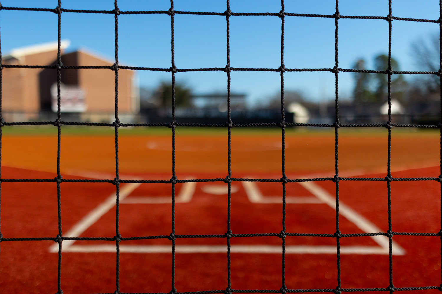 Black netting in front of a softball field's batter's box