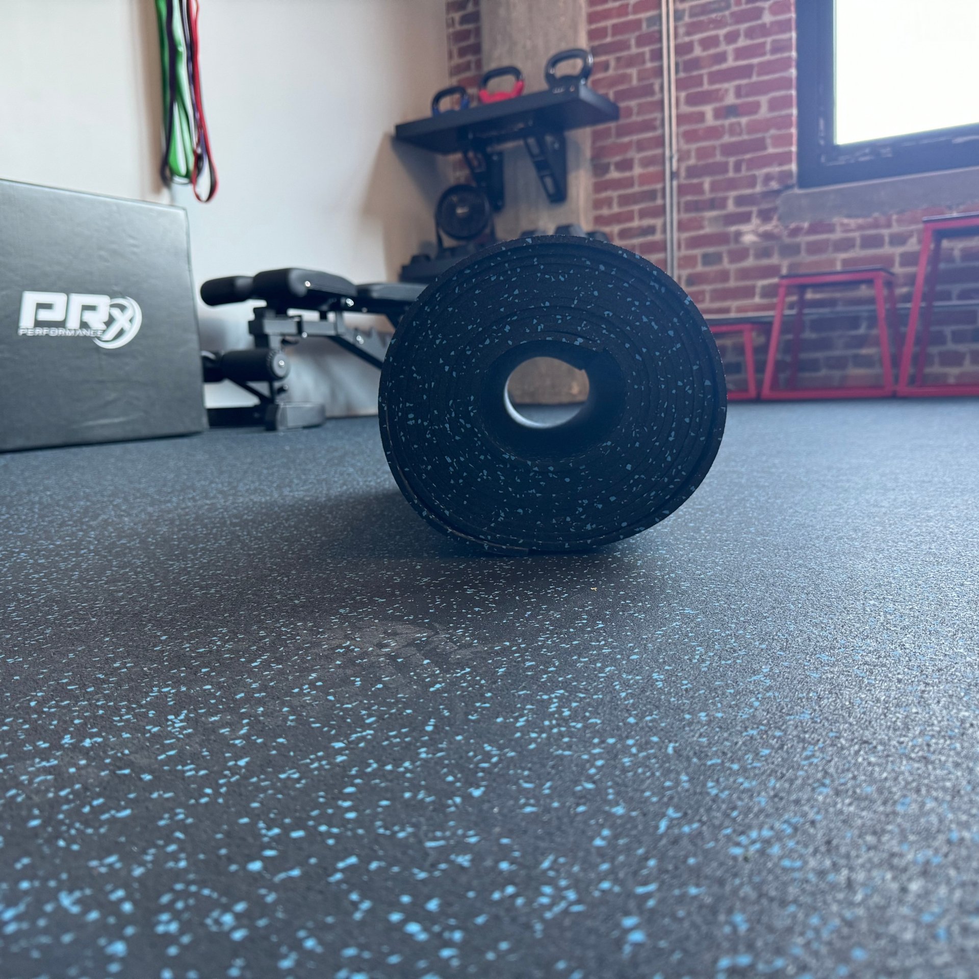 A roll of blue-fleck rubber flooring in a home gym